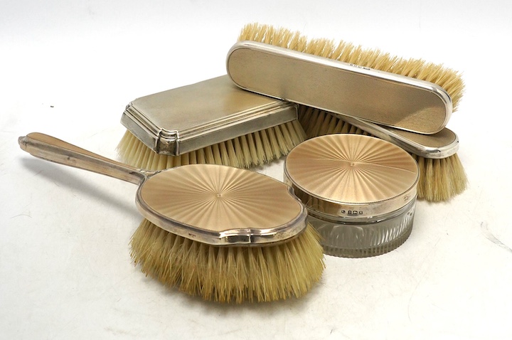 Nine assorted mid 20th century silver mounted dressing table items including a hand mirror, brush and powder jar with enamel, jar diameter 86mm. Condition - poor to fair